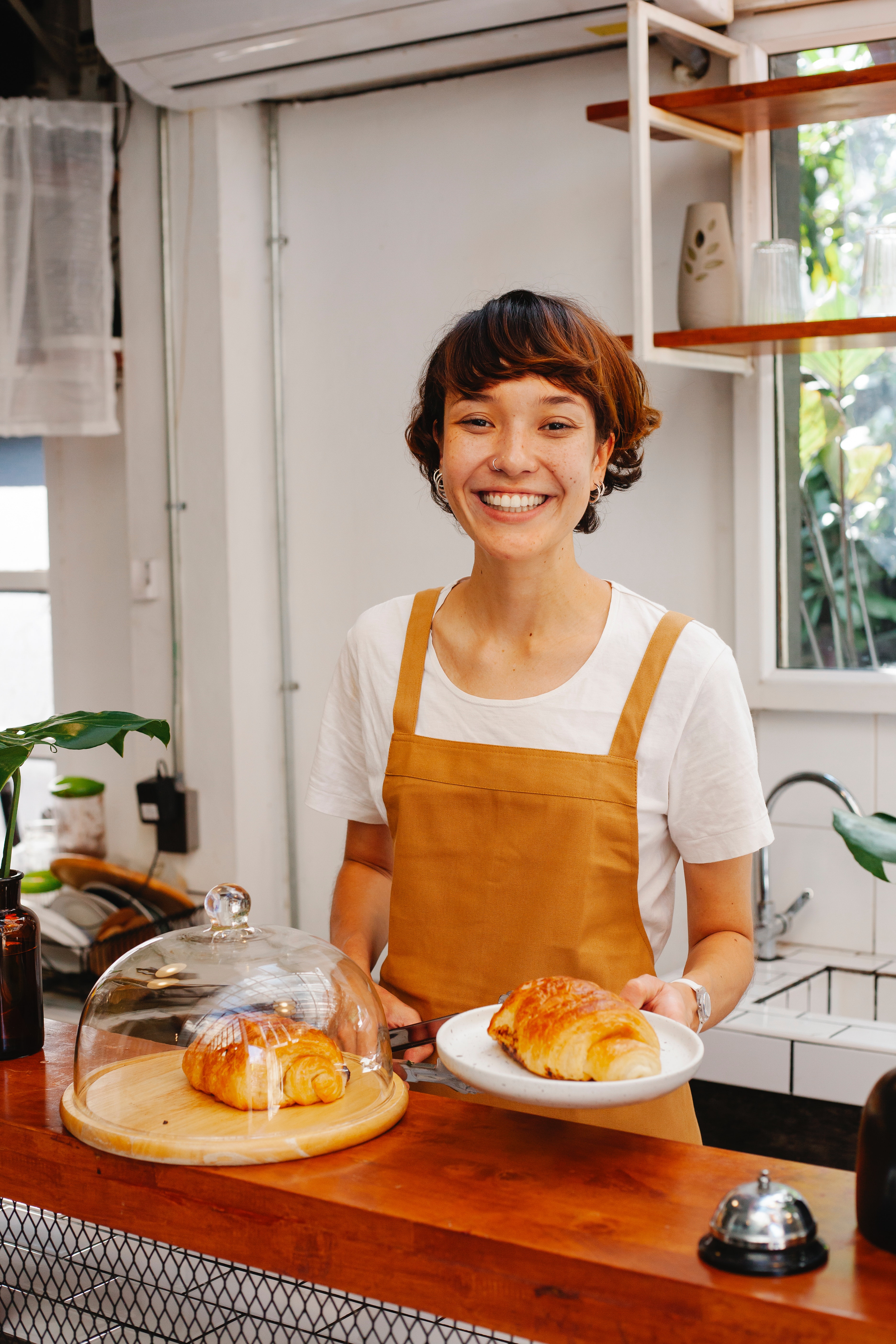 smiling server with apron handing a fresh croissant